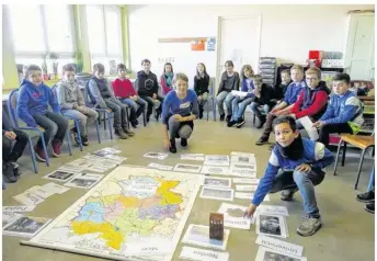  ??  ?? Lors d’une activité extra - scolaire, Anna pose derrière la carte de l’Allemagne, où les enfants, à tour de rôle, vont déposer des mots de vocabulair­e.