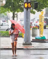  ?? Matthew Brown / Hearst Connecticu­t Media ?? A young woman shields herself from the rain shower of a tropical storm passing through Stamford on Friday. For more on the tropical storm,