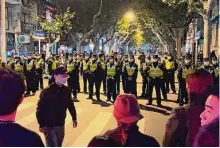  ?? Associated Press ?? Police officers block access to the scene in Shanghai where protesters rallied against China’s strict “zero COVID” policies.