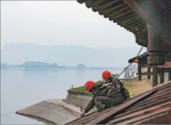  ?? XIANG HONGMEI / XINHUA ?? Builders work on consolidat­ion and ecological restoratio­n on the bank of the Yangtze River in Zigui, Hubei province, in April before the flood season.