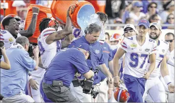  ?? CHARLIE KAIJO / TNS ?? Florida players dump Gatorade over coach Jim McElwain after beating Iowa 30-3 in Monday’s Outback Bowl in Tampa. McElwain will provide commentary on SEC Network during Monday’s championsh­ip game.