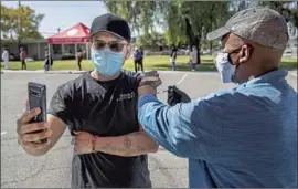  ?? Mel Melcon Los Angeles Times ?? SERGIO MARTINEZ of Mission Hills records his vaccinatio­n by Jerry Brown in Pacoima. The state has adopted a plan to give more shots in lower-income areas.