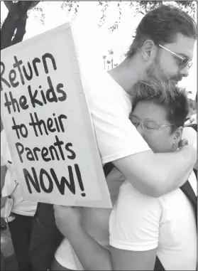  ?? AP Photo/David J. Phillip, File ?? Protest: In this June 25, 2018, file photo, Diana Jung Kim, right, and Homer Carroll, both from Houston, hug during a protest outside the U.S. Border Patrol Central Processing Center in McAllen, Texas. More than 50 immigrant children under age 5 will be reunited with their parents by Tuesday's court-ordered deadline for action by Trump administra­tion and the families will then be released into the U.S., a government attorney said Monday.