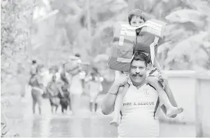  ?? — Gambar Manjunath Kiran/AFP ?? SELAMAT: Anggota bomba dan penyelamat Kerala memikul kanak-kanak mengharung­i air banjir semasa operasi menyelamat di kampung Annamanada di Daerah Thrissur, di negeri Kerala, selatan India kelmarin.