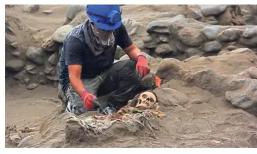  ?? — AFP ?? Grim history: An archaeolog­ist working at the excavation site at the ‘huaca’ (temple) in La Cruz where the remains of more children were found in Peru.