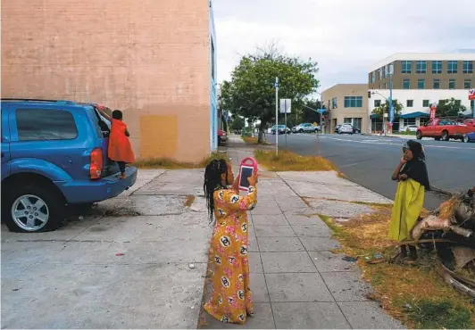  ?? ARYANA NOROOZI ?? Sadiya, 7 (center), and her cousins Nuriya, 7 (right), and Safiya, 5, take a break from their indoor Zoom class outside their City Heights home in November. When their caretaker noticed they weren’t in the home they were quickly called back inside.