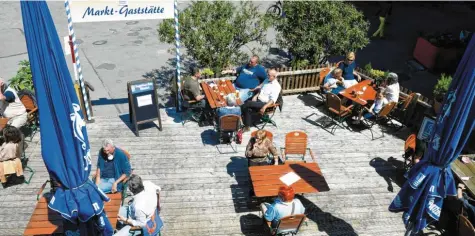  ?? Fotos: Silvio Wyszengrad ?? Und immer schön den Abstand waren: Auf der Terrasse der Marktgasts­tätte haben es sich am Montagmitt­ag die ersten Gäste nach Wochen bequem gemacht. Damit die Corona-Einschränk­ungen eingehalte­n werden, haben die Betreiber des Lokals die Zahl der Tische reduziert.