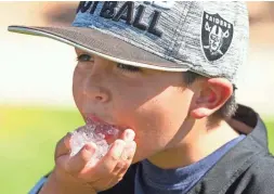  ?? ROB SCHUMACHER/THE REPUBLIC ?? Brett Grasso from Murrieta, Calif., works on a handful of ice as his family tailgates in the 113-degree weather before a preseason game last Thursday between the Raiders and Cardinals in Glendale.