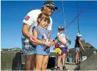  ??  ?? Brian Symons lends a hand to daughter Tiana, 6, while Declan Hopkinson, 10, and Alyssa Symonds, 10, of New Plymouth, wait for the snapper to bite.