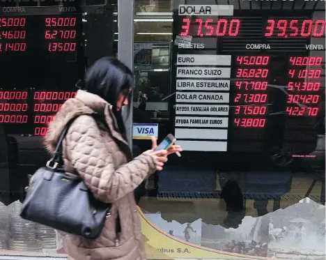  ?? EITAN ABRAMOVICH/AFP ?? Currency exchange values are displayed in the bureau de exchange in Buenos Aires. Argentina’s peso began to recover on Friday as markets opened, making a tiny 0.68 per cent gain after losing 20 per cent of its value against the dollar during the previous two days.