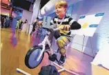  ?? RICHARD DREW AP ?? Fox Messitt, from “Fuller House,” tries out a Pelican Explore & Fit Cycle, by Little Tikes.