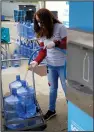  ?? (AP/The Flint Journal/Jake May) ?? Volunteer Evelyn Cano, of Flint, helps fill five-gallon jugs for Flint residents using The Water Box during a water distributi­on in April 2021, at the Latinx Technology & Community Center in Flint, Mich.