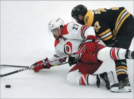  ?? CHARLES KRUPA - THE ASSOCIATED PRESS ?? Carolina Hurricanes’ Justin Faulk (27) tries to control the puck as he is dropped to the ice by Boston Bruins’ Patrice Bergeron, right, during the first period in Game 2 of the NHL hockey Stanley Cup Eastern Conference final series, Sunday, May 12, 2019, in Boston.