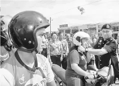  ??  ?? Mohd Sar’ie puts on a free helmet on a female rider during the launch of ‘Ops Selamat’.