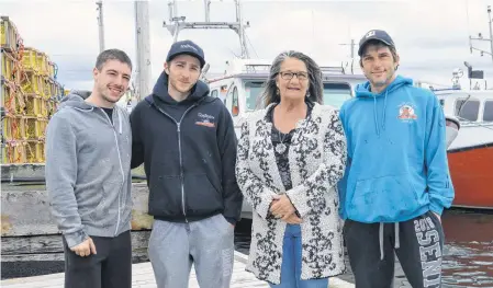  ?? JEREMY FRASER/CAPE BRETON POST ?? Family members stand in front of fishing boats near Ballast Grounds Fisheries at the North Sydney Wharf. Lobster fishing season begins in area 27 on Friday and fishermen are worried about the uncertaint­y of the season because of COVID-19. From left are Dylan MacKinnon, Scott MacKinnon Jr., Marlene Brogan and Roger Penny.