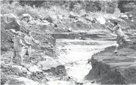  ?? (Czar Dancel) ?? EVACUEES prepare to catch a sack of rice from a fellow evacuee on the other side of a gully where lahar is flowing following overnight rains near the slopes of Mayon Volcano in Camalig, Albay.