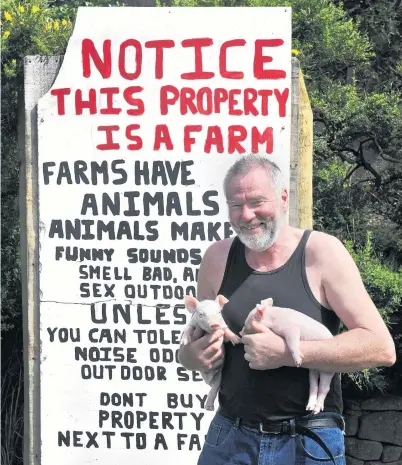  ?? PHOTO: CHRISTINE O’CONNOR ?? Rural realities . . . Pig farmer Pieter Bloem installs an educationa­l sign outside his Otago Peninsula property.