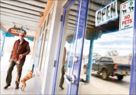  ?? DANIEL PEARSON/Taos News ?? A dog and his owner look into Sushi Siam Taos, where there is a sign on the door banning non-service animal pets, on Friday (April 5).