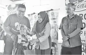  ??  ?? Jainab (middle) presenting school aid to one of the children during the Bach to School Program yesterday.