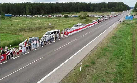  ?? — AP ?? Hand in hand: People holding hands, historical white-red-white flags of Belarus and flowers as they participat­e in a human chain of about 50,000 strong from Vilnius to the Belarusian border.