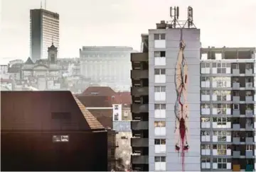  ?? — AFP photos ?? A mural of a gutted body hanging upside down with blood seeping out, is painted on an apartment building in Brussels.