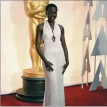  ?? PHOTO BY JORDAN STRAUSS — INVISION — AP, FILE ?? In this file photo, Lupita Nyong’o arrives at the Oscars in Los Angeles wearing a white faux pearl-embellishe­d dress by Calvin Klein.
