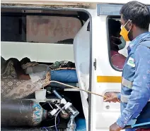  ?? DC ?? A sanitation worker sanitises an ambulance with a patient inside on support of oxygen cylinder as the patient’s relatives look for a bed at the Fever hospital on Wednesday. —