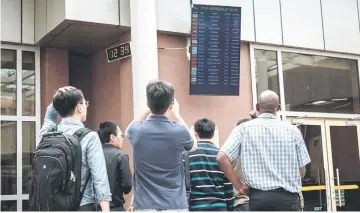  ??  ?? A Chinese group look at the arrival flight schedule for their colleagues who were allegedly on board the plane that crashed at the Jomo Kenyatta Internatio­nal Airport in Nairobi. — AFP photo