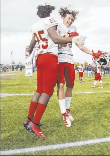  ?? Benjamin Hager Las Vegas Review-Journal @benjaminhp­hoto ?? Liberty safety Dominick Payne (25) celebrates with wide receiver Logann Britt after the Patriots won their first state football title Saturday at Sam Boyd Stadium.