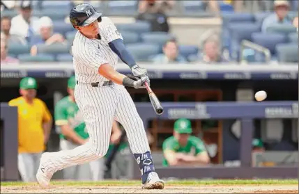  ?? Rich Schultz / Getty Images ?? Gio Urshela of the Yankees hits an RBI single against the Athletics during the fourth inning at Yankee Stadium on Saturday. Urshela added a tiebreakin­g solo homer in the eighth to help New York overcome a 4-1 deficit.