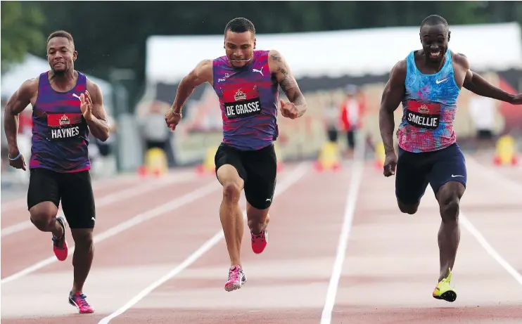  ?? THE CANADIAN PRESS ?? Andre De Grasse, centre, of Toronto, powers across the finish line to win gold in the 100m event at the national track and field championsh­ips in Ottawa.