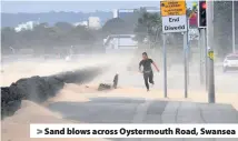  ??  ?? &gt; Sand blows across Oystermout­h Road, Swansea