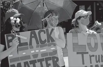  ?? SARAH GORDON/THE DAY ?? From left, Derek Tavares of New London, friend Mara Gutt and his mother, Robin Harris, listen to a speaker during a vigil to honor Black trans lives in 2020 at New London City Hall. The inaugural event, organized by OutCT, honored queer and trans people of color, both past and present.