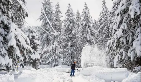  ?? Jenna Schoenfeld / New York Times ?? A resident clears snow from the road on Friday during a break from the storm in Pine Mountain Club, Calif., after a rare blizzard in Southern California dumped significan­t snow overnight.