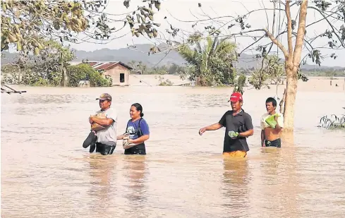  ?? AFP ?? Residents wade through a flooded highway caused by heavy rains due to Typhoon Phanfone in central Philippine­s on Wednesday.