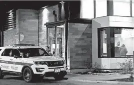  ?? JOHN J. KIM/CHICAGO TRIBUNE ?? Police officers work inside their patrol SUV on March 10 as Phillip Sanchez, a ride-share driver who had his vehicle carjacked by two passengers at a South Side fast-food restaurant, talks on his phone.