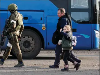  ?? AP ?? NOT GETTING BETTER: A man and a girl who left a shelter in the Metallurgi­cal Combine Azovstal walk to a bus escorting by a serviceman of the Russian Army in Mariupol, in territory under the government of the Donetsk People’s Republic, eastern Ukraine, on Friday.