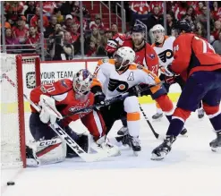  ?? — AFP ?? WASHINGTON: Wayne Simmonds #17 of the Philadelph­ia Flyers slides into goalie Braden Holtby #70 of the Washington Capitals in the first period at Verizon Center on Saturday in Washington, DC.