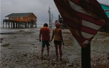  ?? Godofredo A. Vásquez / Staff photograph­er ?? Adam Maubach, left, and Jo Dove check on the erosion caused by Tropical Storm Beta’s surge in Surfside Beach on Monday.