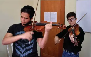  ?? (Jim Wyss/TNS) ?? PEDRO CHANGIR (left) and Zabdiel Hernandez rehearse before teaching music classes in Lima, Peru.