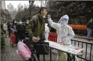  ?? AP ?? A man gets a throat swab during a mass COVID-19 test at a residentia­l compound in Wuhan in central China’s Hubei province.