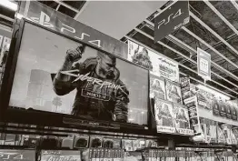  ?? Kazuhiro Nogi / Getty Images ?? A screen showing a promotiona­l video for the Cyberpunk 2077 game for the Sony Playstatio­n is seen in the gaming section of a shop in Tokyo.