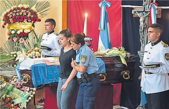  ?? (ANDRÉS BLANCO) ?? Último adiós. Una de las hermanas de Ferraro recibe la asistencia de una policía, durante el velatorio de ayer en San Carlos Minas.