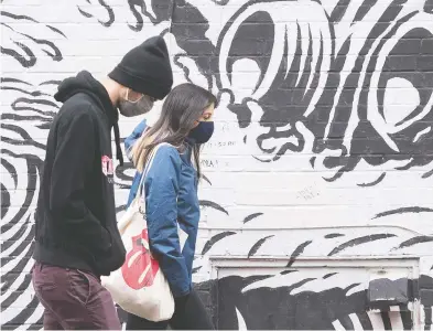  ?? GRAHAM HUGHES / THE CANADIAN PRESS ?? People wear face masks as they walk by a mural in Montreal on Sunday. Daily case counts in Canada show
the spread of COVID-19 continues to accelerate.