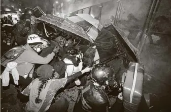  ?? Marcio Jose Sanchez / Associated Press ?? Demonstrat­ors shield themselves with umbrellas as federal officers fire tear gas outside the federal courthouse in downtown Portland, Ore., during a Black Lives Matter protest Friday.