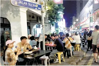  ?? John Brunton/South China Morning Post ?? Diners pack out streetside eateries in Kuala Lumpur’s Chinatown.
