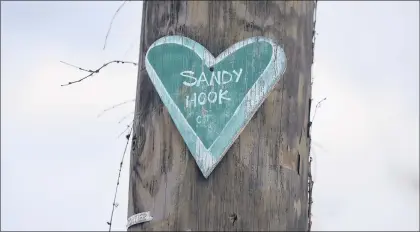  ?? CLOE POISSON/HARTFORD COURANT ?? A green heart is tacked to a telephone pole in Newtown in 2017 on the fifth anniversar­y of the shooting at Sandy Hook Elementary School. The school’s colors are green and white.