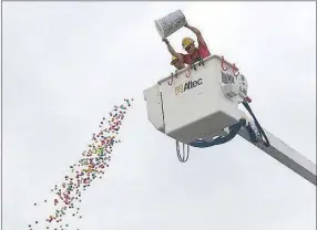  ?? Westside Eagle Observer/SUSAN HOLLAND ?? Colorful balls are dropped from the bucket of a crane lifted high above Gravette Main Street. The balls were marked with numbers and a total of $850 was awarded to holders of prizewinni­ng numbers. Two money drops were sponsored by the Bank of Gravette.