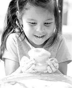  ??  ?? Luna, four, holds pottery she made at Pots-n-Prints’ work station at an arts festival in Big Spring, Texas. — WP-Bloomberg photos