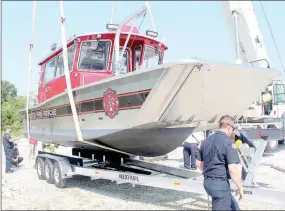  ?? TIMES photograph by Keith Bryant ?? Firefighte­rs with Northeast Benton County Volunteer Fire-EMS Department help guide the new fire-rescue boat as it is lowered onto the department’s trailer. The Northeast Benton County Volunteer Fire Department took delivery of its new firerescue boat Wednesday, Aug. 9. NEBCO board chair Kara Funk said the boat, which cost $365,000, is used for fighting fires, as a mobile fire hydrant on Beaver Lake and for water rescues.